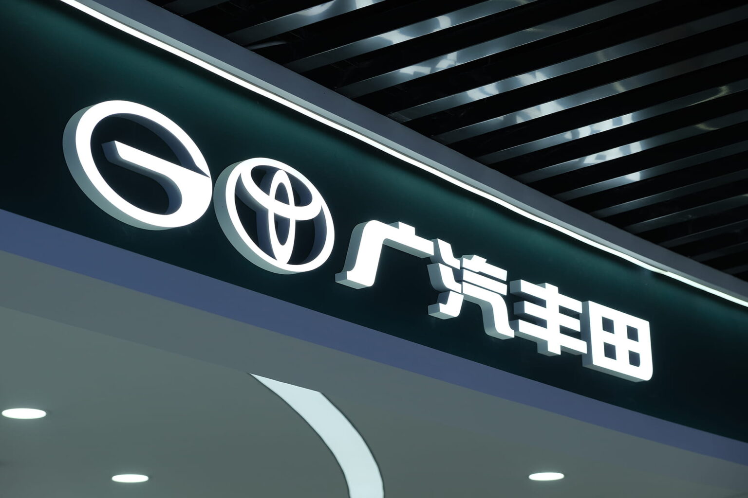 Illuminated GAC and Toyota logos with the Chinese characters for GAC Toyota on a dark green dealership sign.